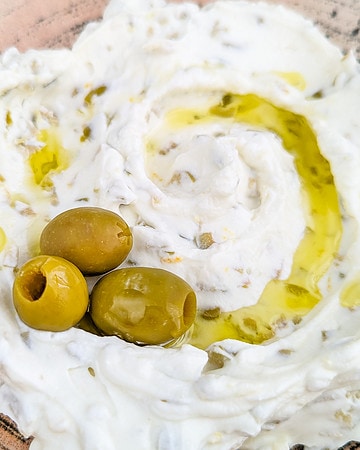 Close look of olive dip with 3 olives and olive oil.