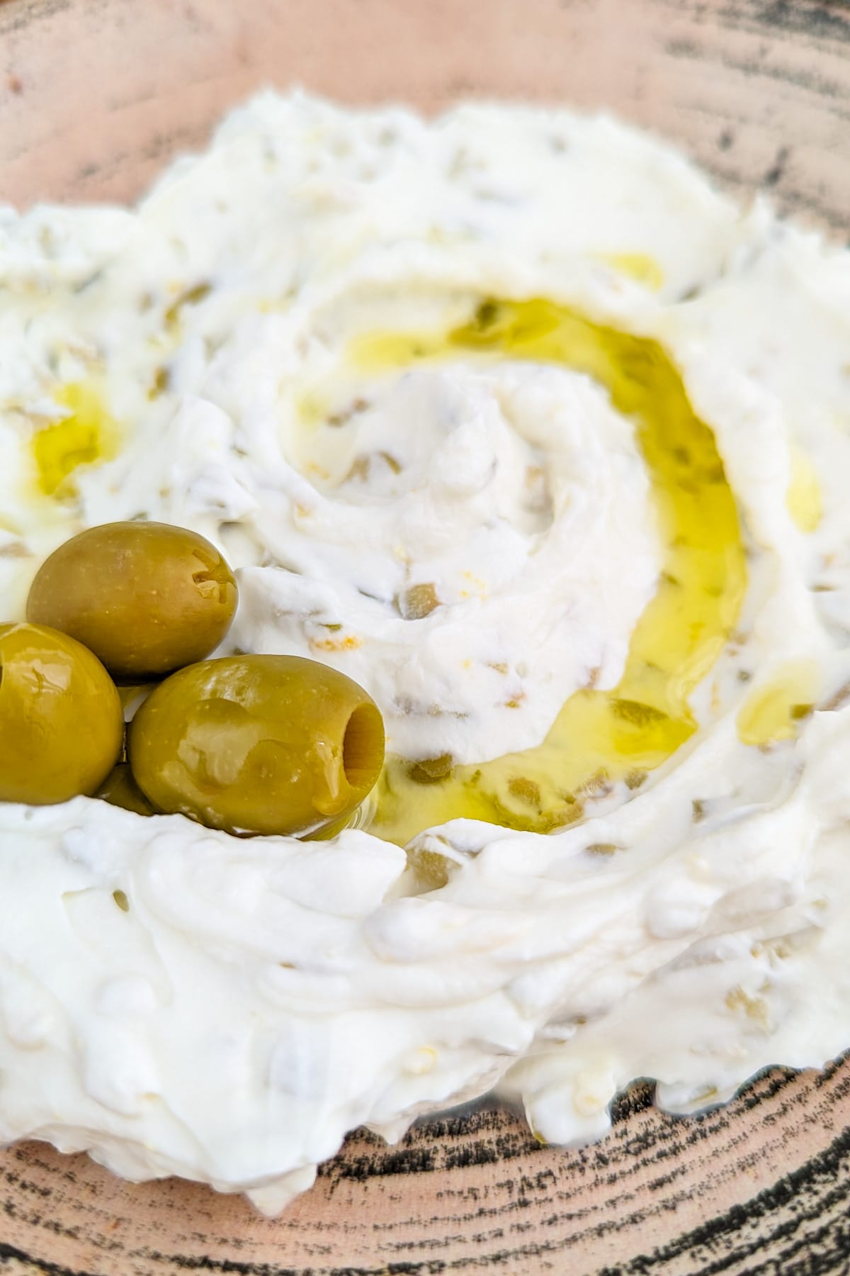 Close look of a vintage plate with 3 olives, olive oil, and olive dip.