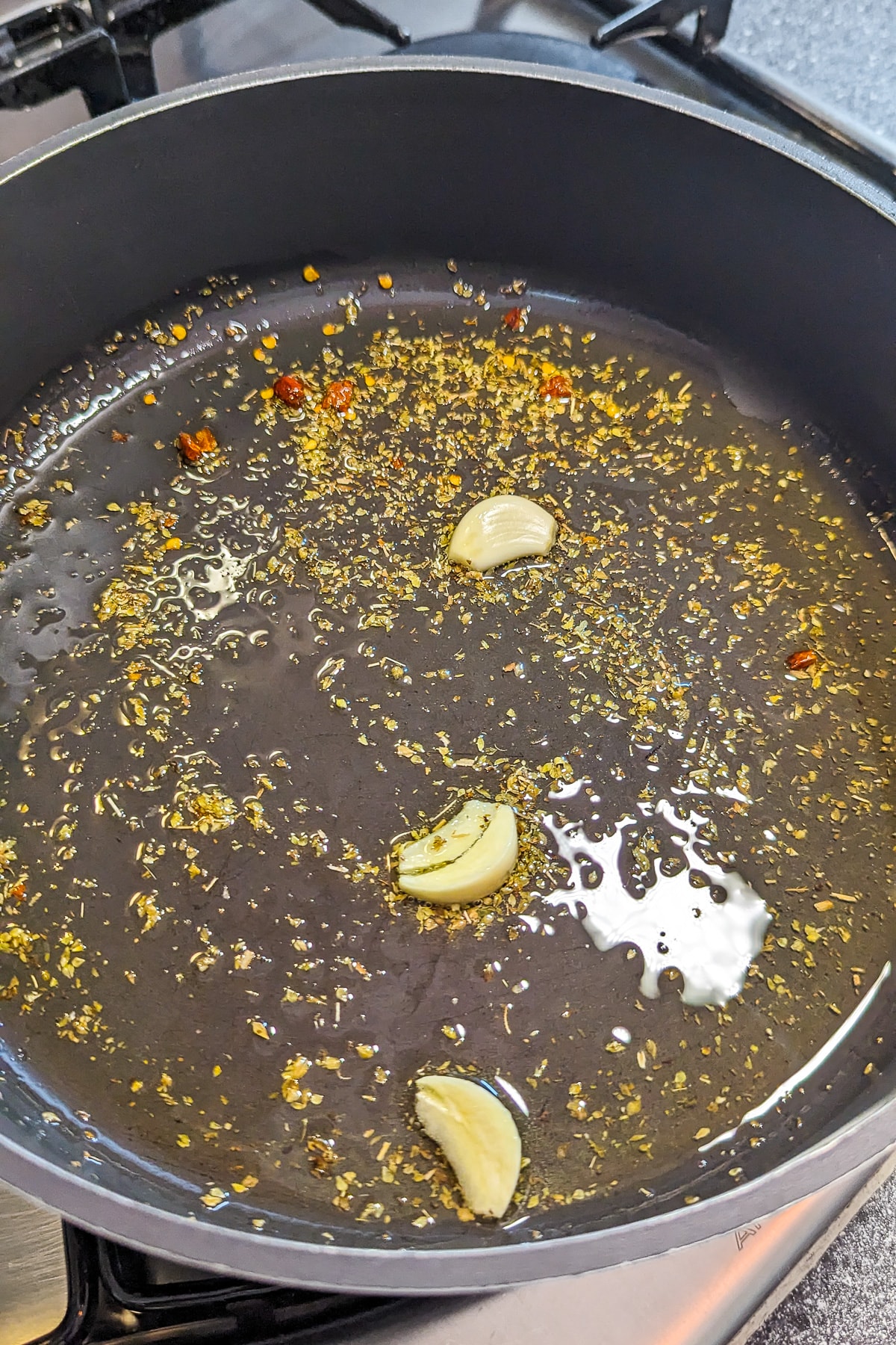 A pan with oil flavored with garlic, dried oregano and black pepper.
