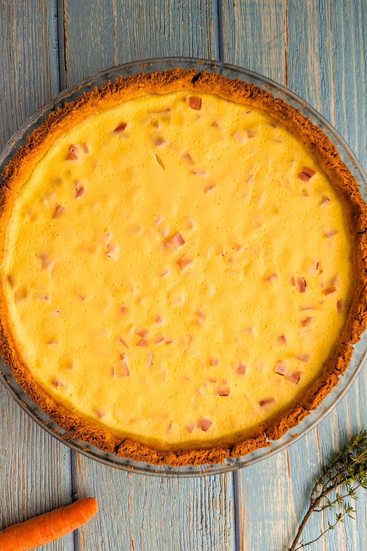 Top view of a 4 ingredient quiche on a blue wooden table.