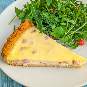 Close look of a slice of 4 ingredience quiche near a green salad.