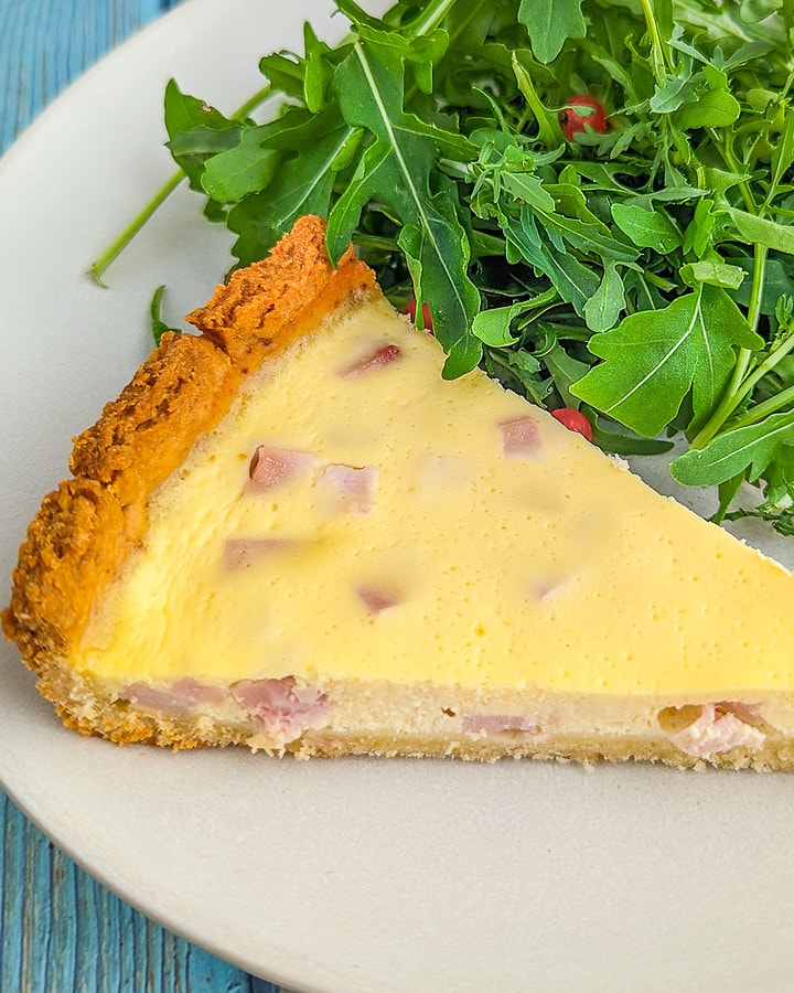 Close look of a slice of 4 ingredience quiche near a green salad.