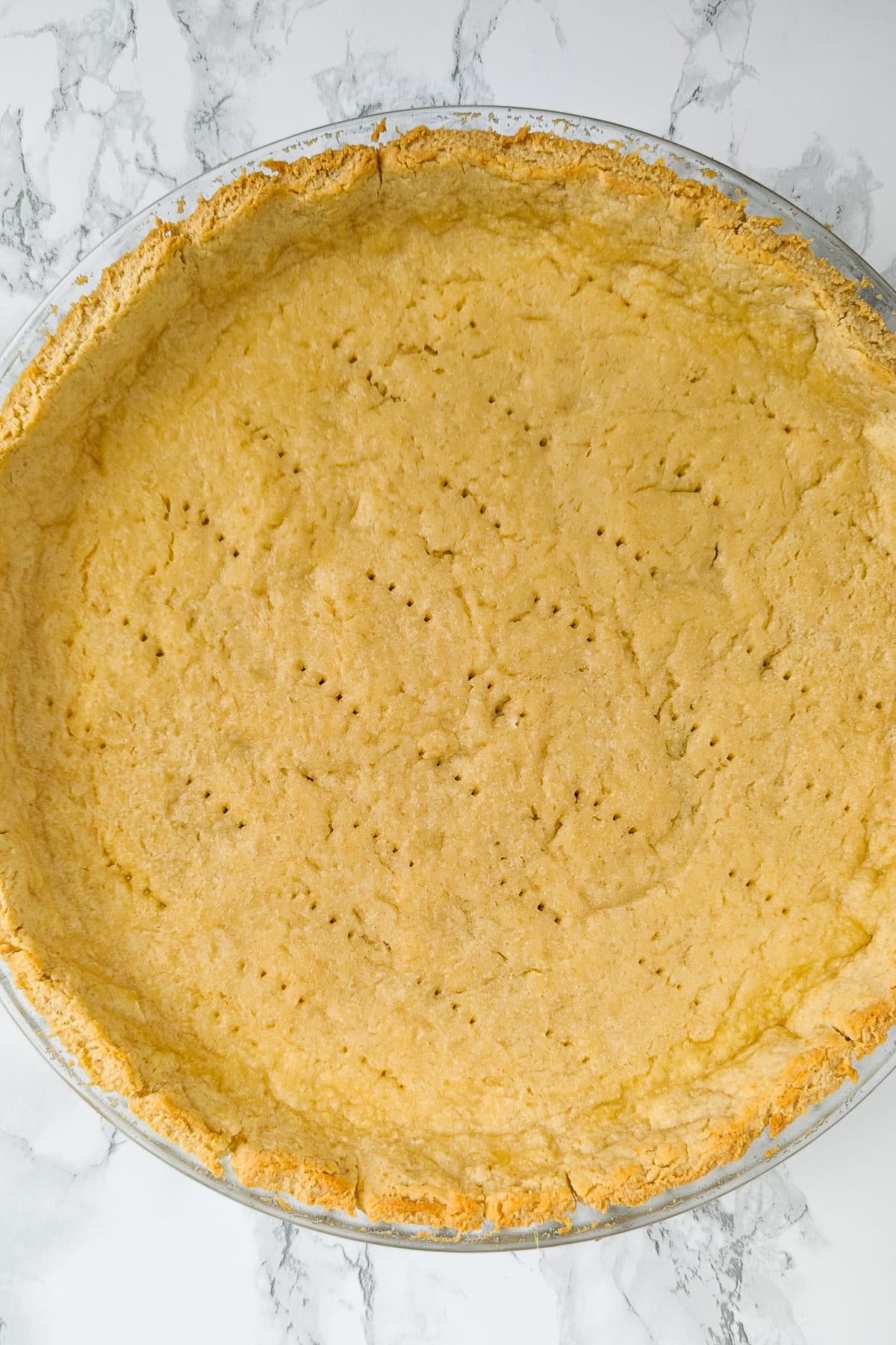 Top view of a plate with baked tart on a white marble background.