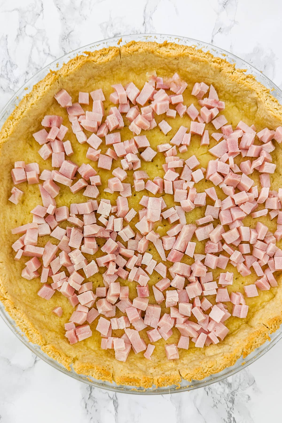 Top view of a tart covered with small pieces of ham.
