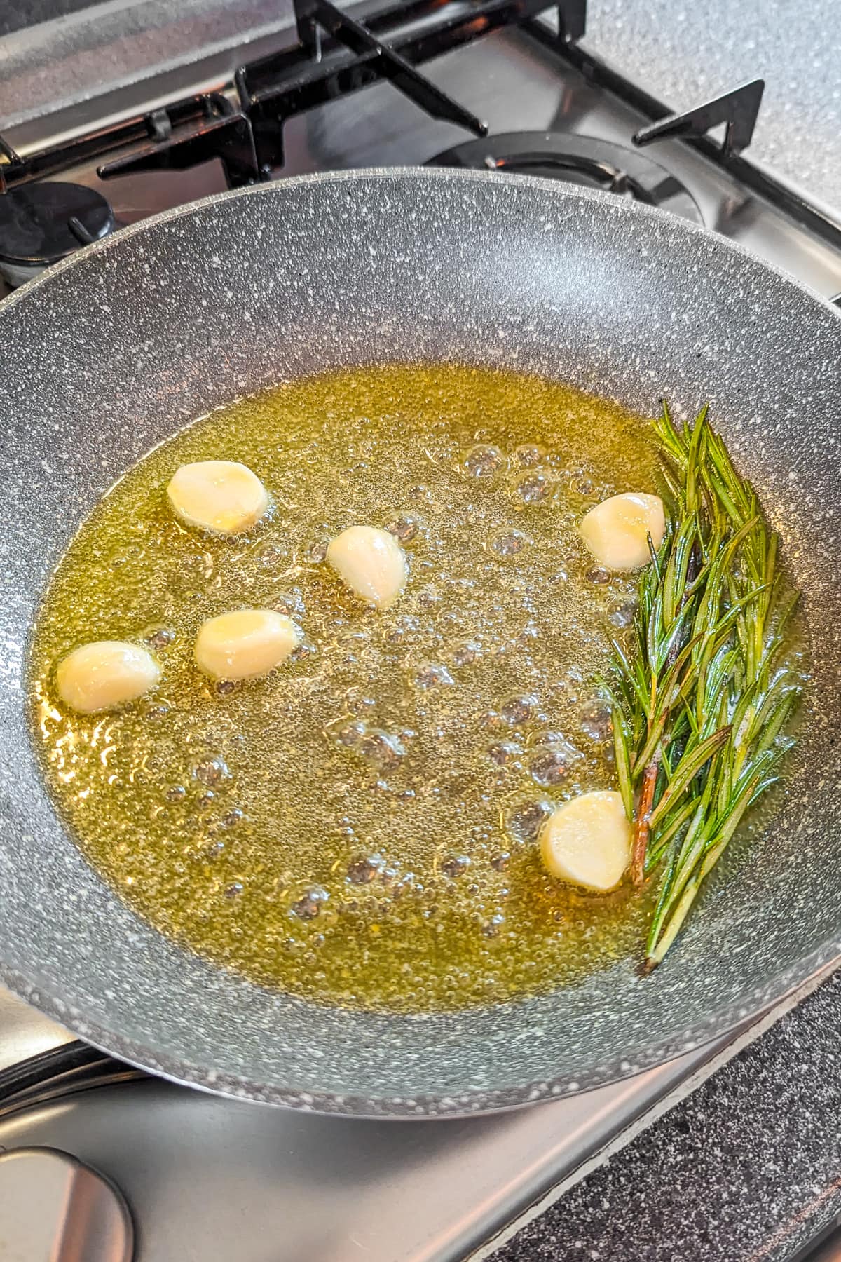 Pan with melted butter flavored with garlic cloves and rosemary.