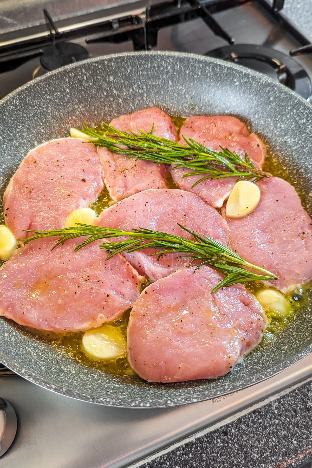 Frying pork chops in flavored melted butter with garlic and rosemary brunches.