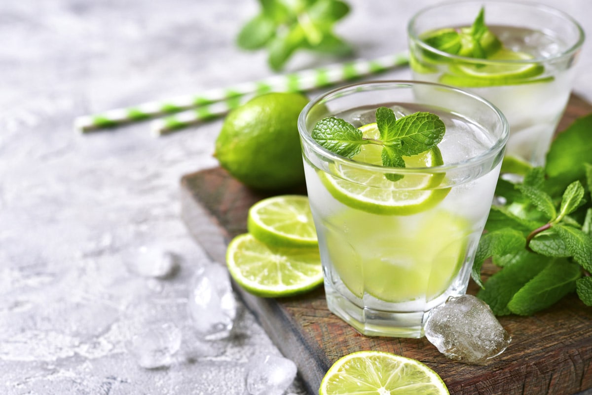 Top view of sparkling water with lime slices, mint and ice cubes.