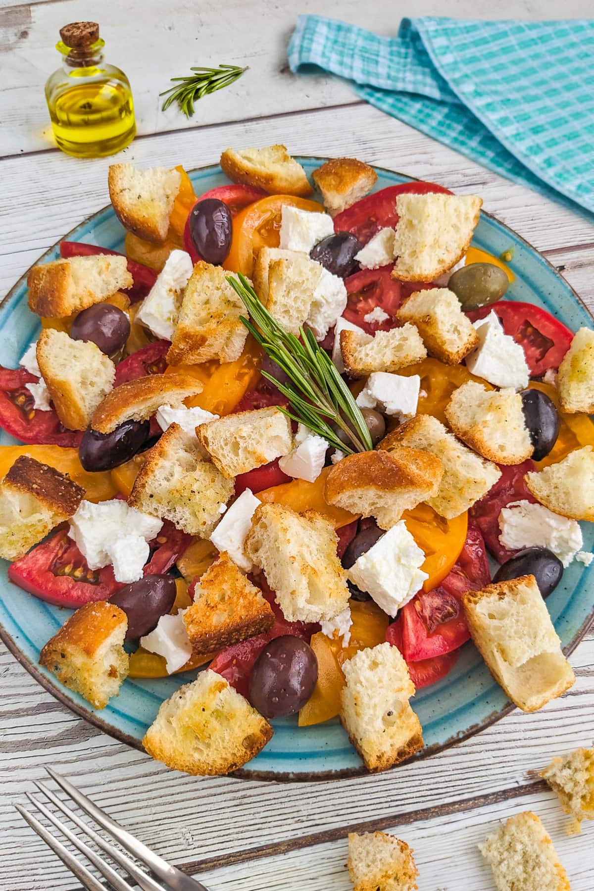 Top view of tomato and feta salad with croutons on a wooden table.