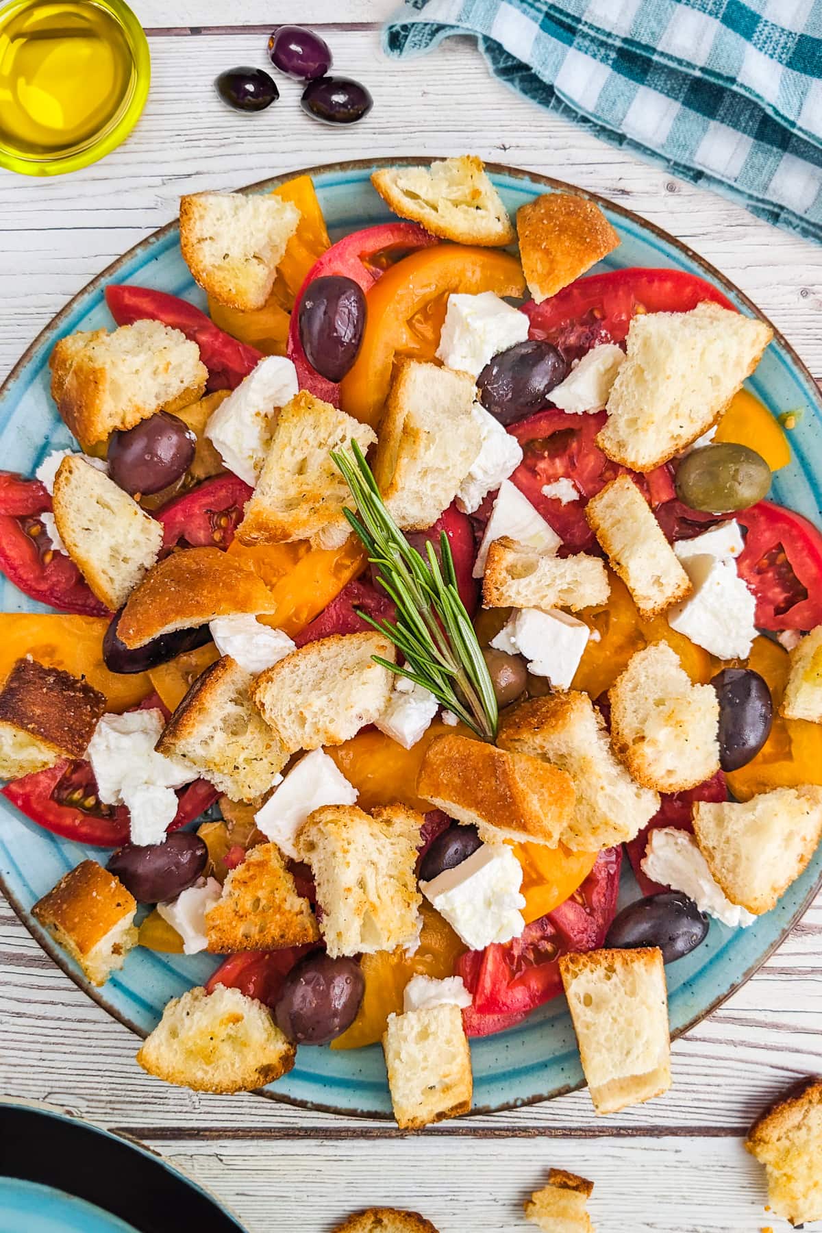Top view of tomato and feta salad with croutons on a wooden table.