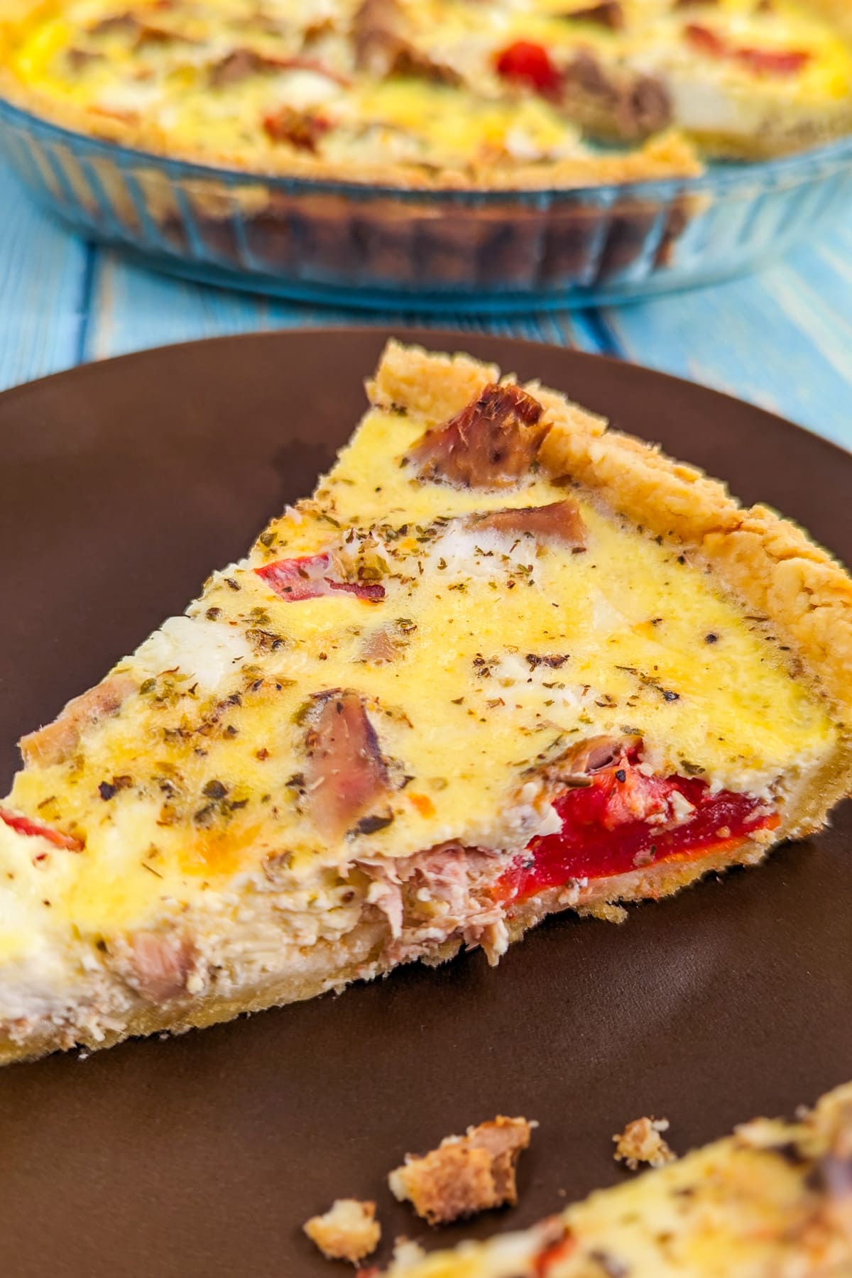 Close look of a slice of tuna quiche on a brown plate.