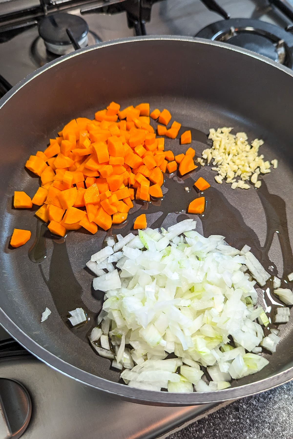 Frying pan with chopped carrots, onions and garlic.