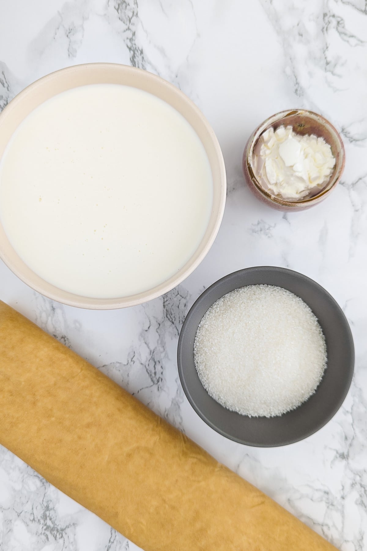 Vanila, cream, sugar and dough on a white marble table.