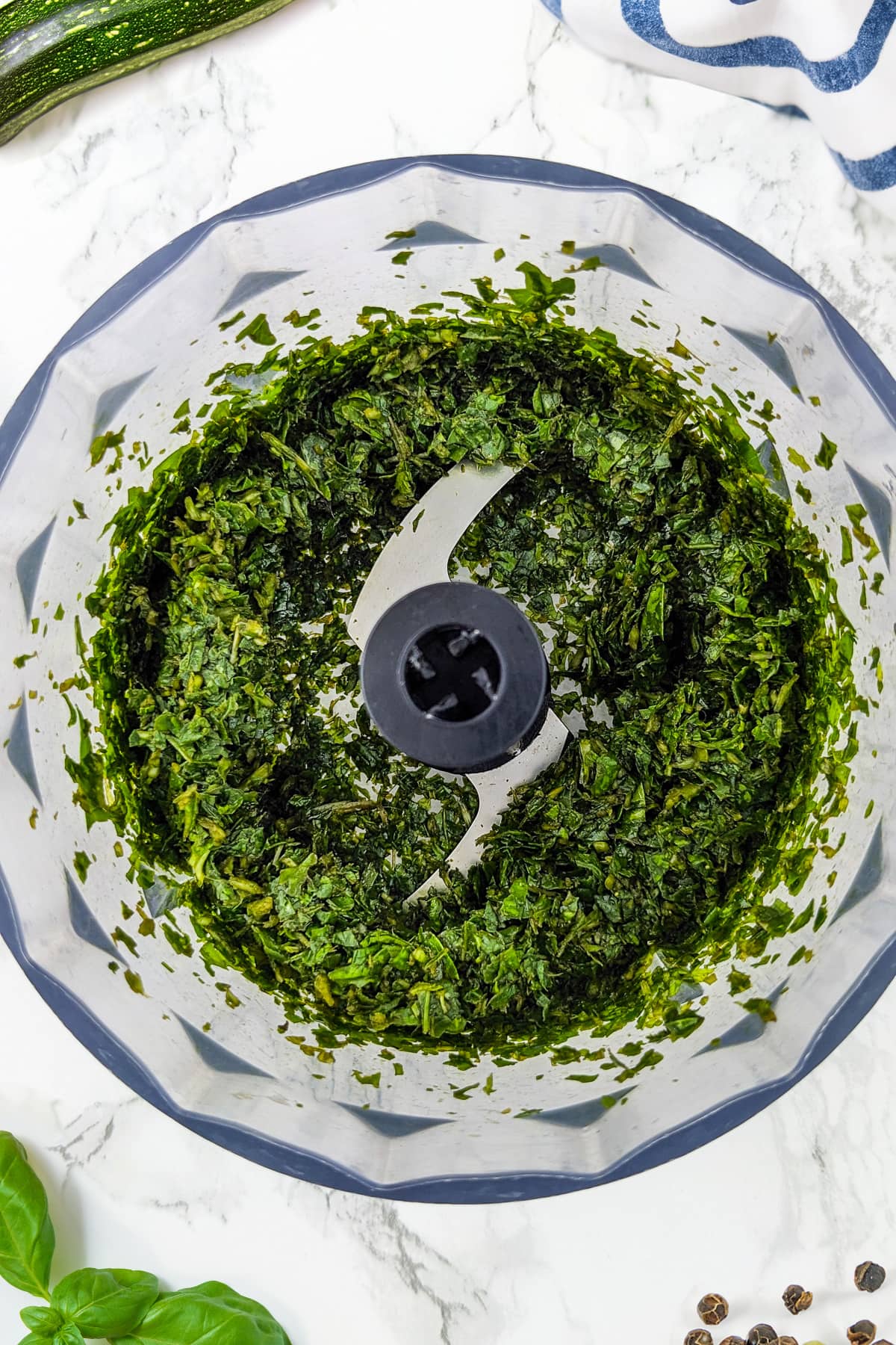 Basil pesto in a table blender on a white marble table.