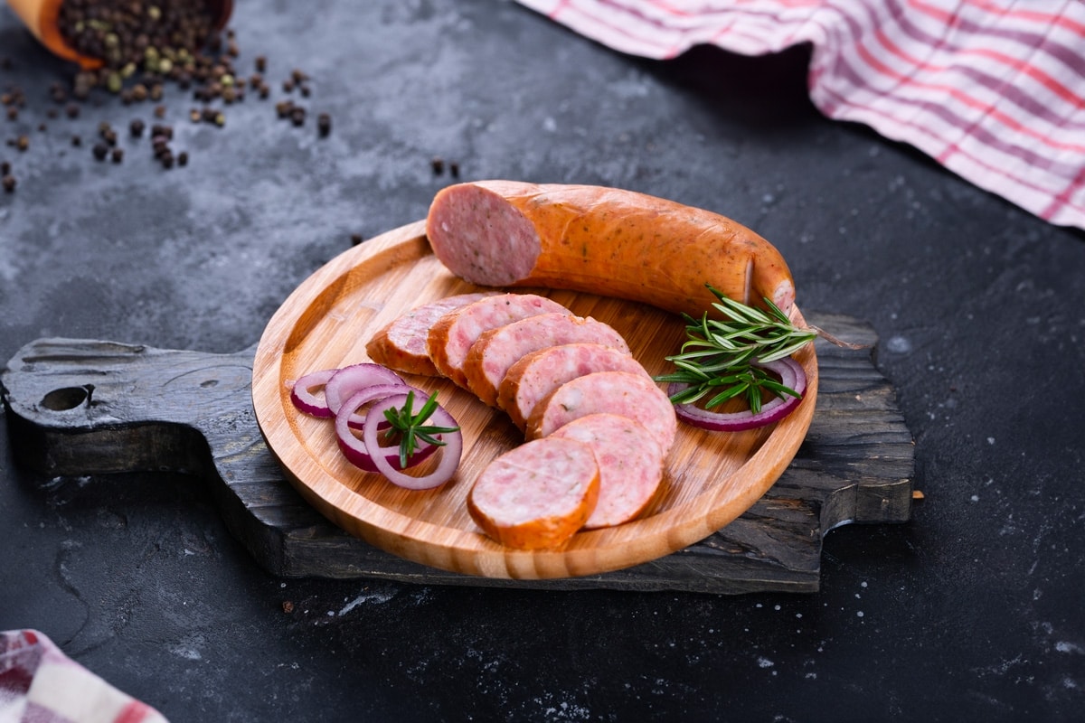 A few slies of Andouille sausagrs on a black wooden board.