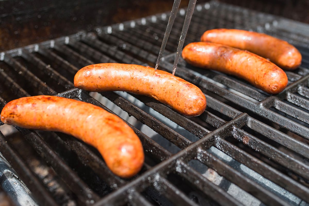 Close look of 4 Androuille sausages on a grill.