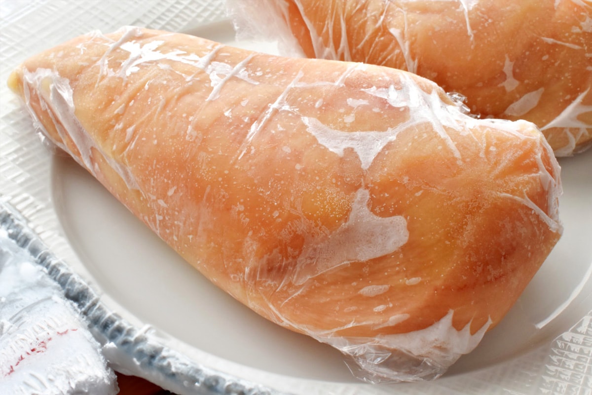 Close look of two frozen chicken breast on a white plate.