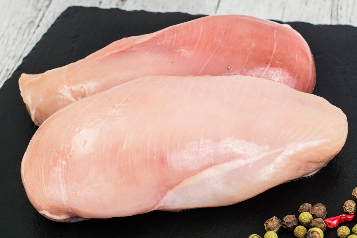 Close look of two frozen chicken breast on a black serving board