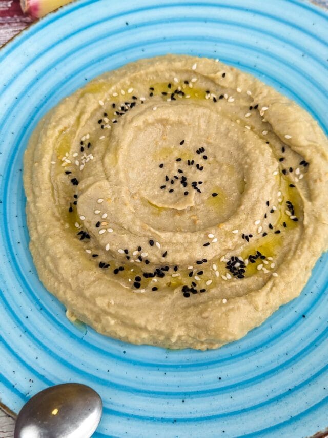 Close view of eggplant dip with tahini in a vintage blue plate.