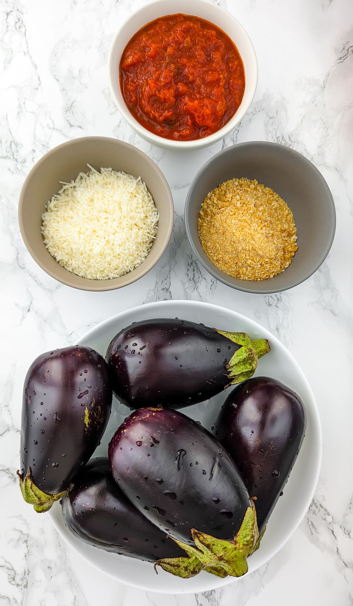 Top view of a plate full with eggplants, breadcrumbs, parmesan and tomato sauce.