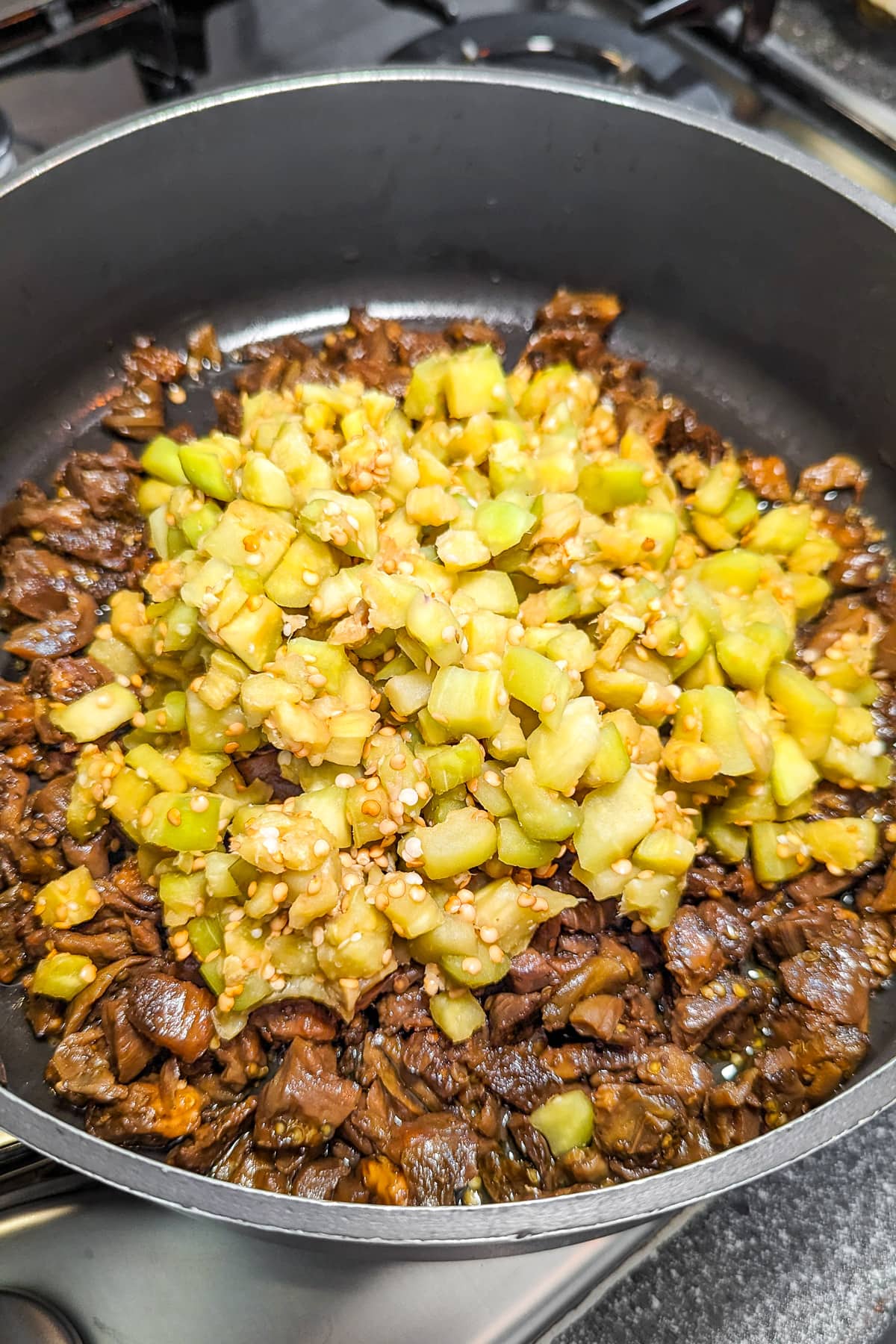 A pan on the stove with cooked diced eggplants.