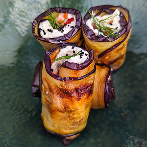 Close view of eggplant and cheese rolls in a green vintage plate.