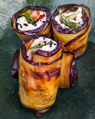 Close view of eggplant and cheese rolls in a green vintage plate.