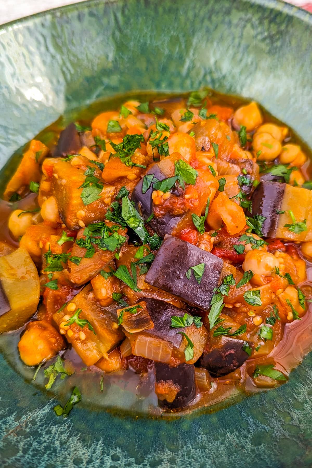 Vintage green plate with eggplant and chickpea stew and freshly chopped parsley.