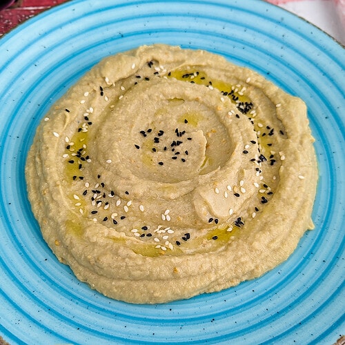Close view of eggplant dip with tahini in a vintage blue plate.