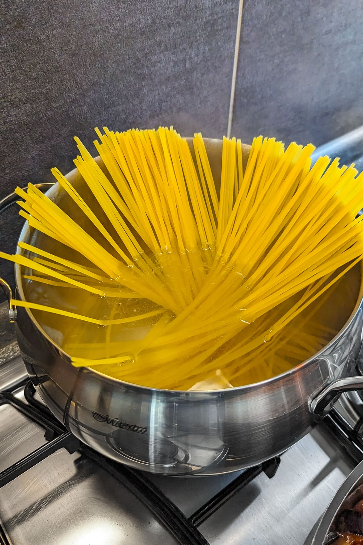 Raw spaghetti in a pot with boiling water on the stove.