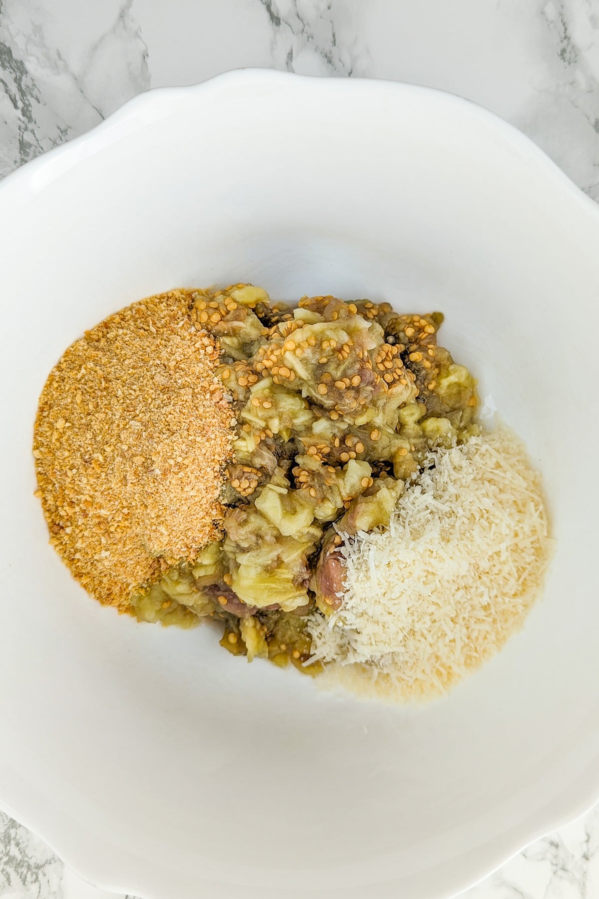 White large bowl with breadcrumbs, eggplant and parmesan.
