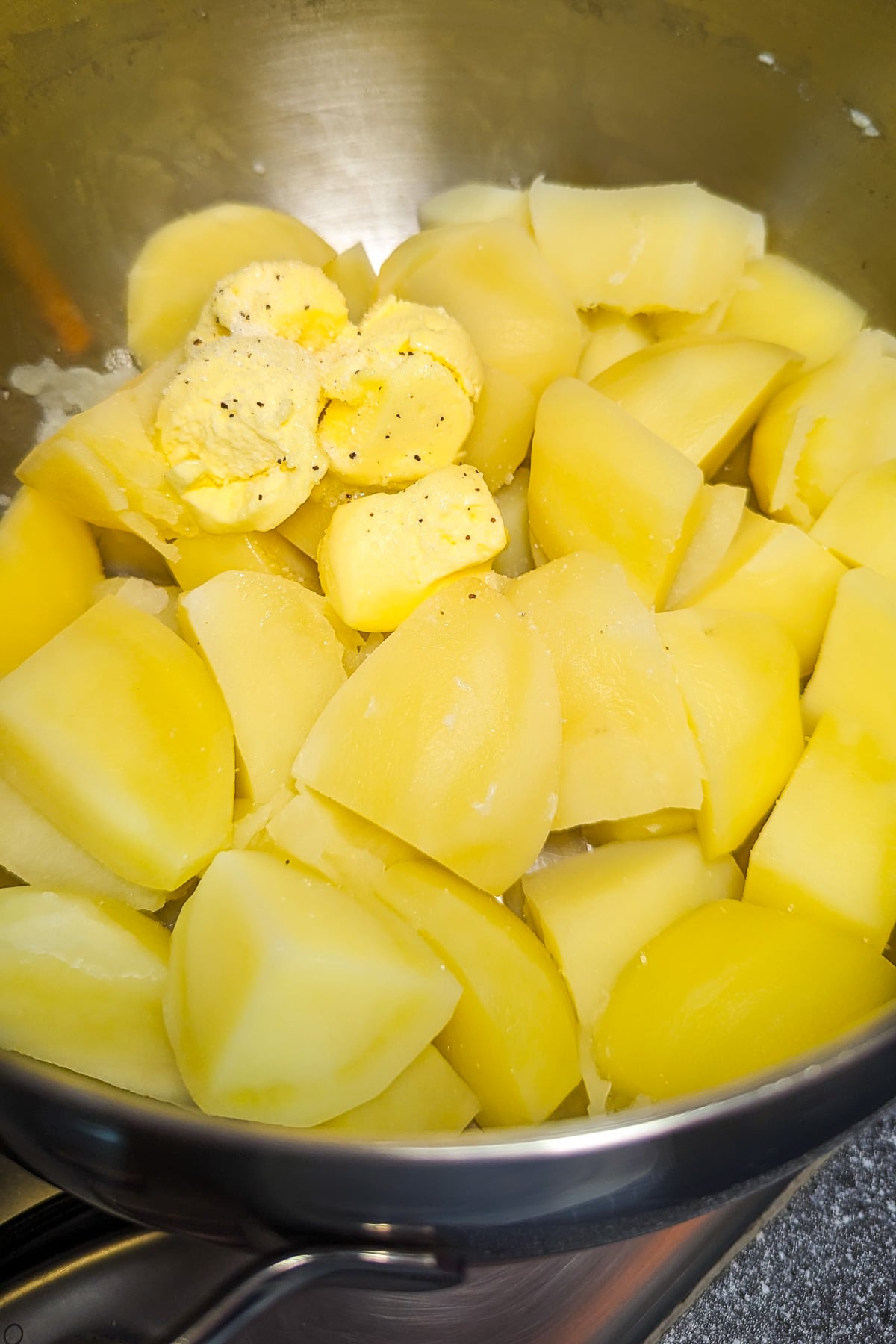 Boiled potatoes with a few cubes of butter on a pan.