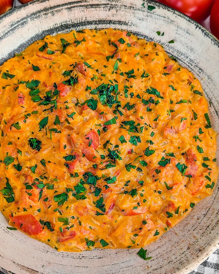 Close view of tomato and onion dip with freshly chopped parsley in a vintage plate.