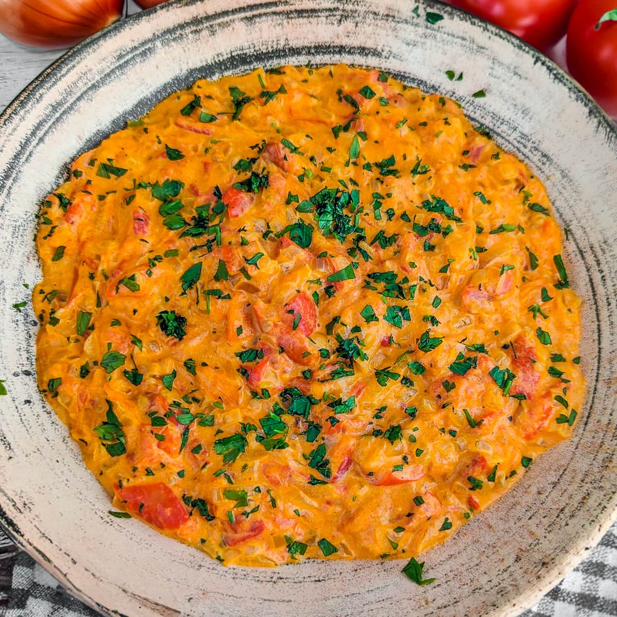 Close view of tomato and onion dip with freshly chopped parsley in a vintage plate.