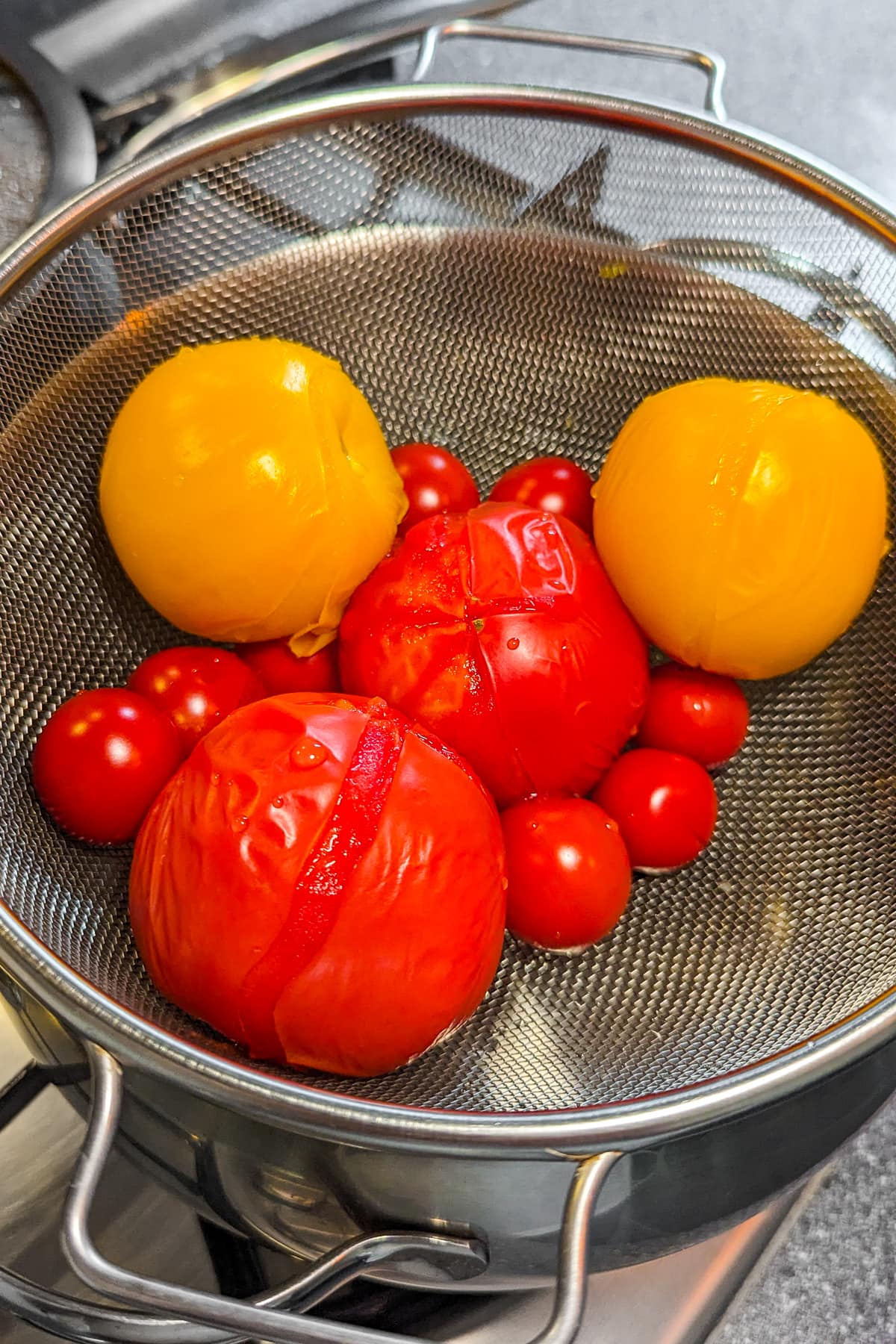 Red and yellow tomatoes that drain on a sieve.