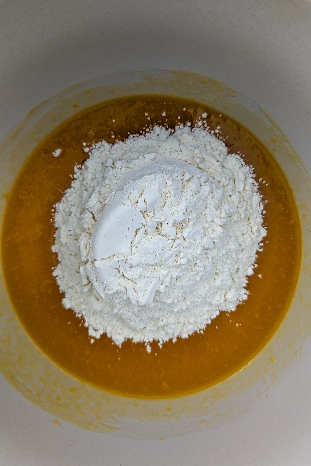Top view of flour over a pumpkin puree in a large bowl.