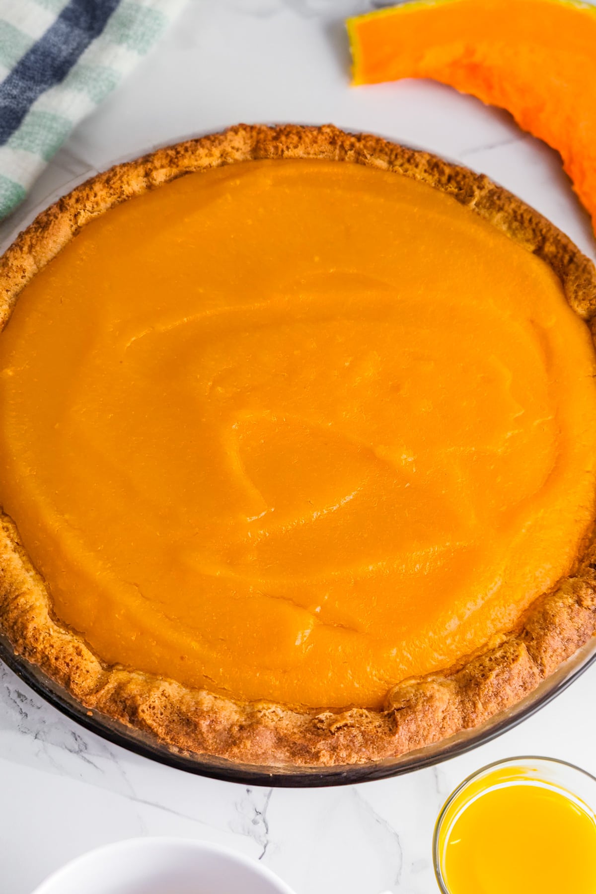 Close look of a pumpkin pie on a white marble table.