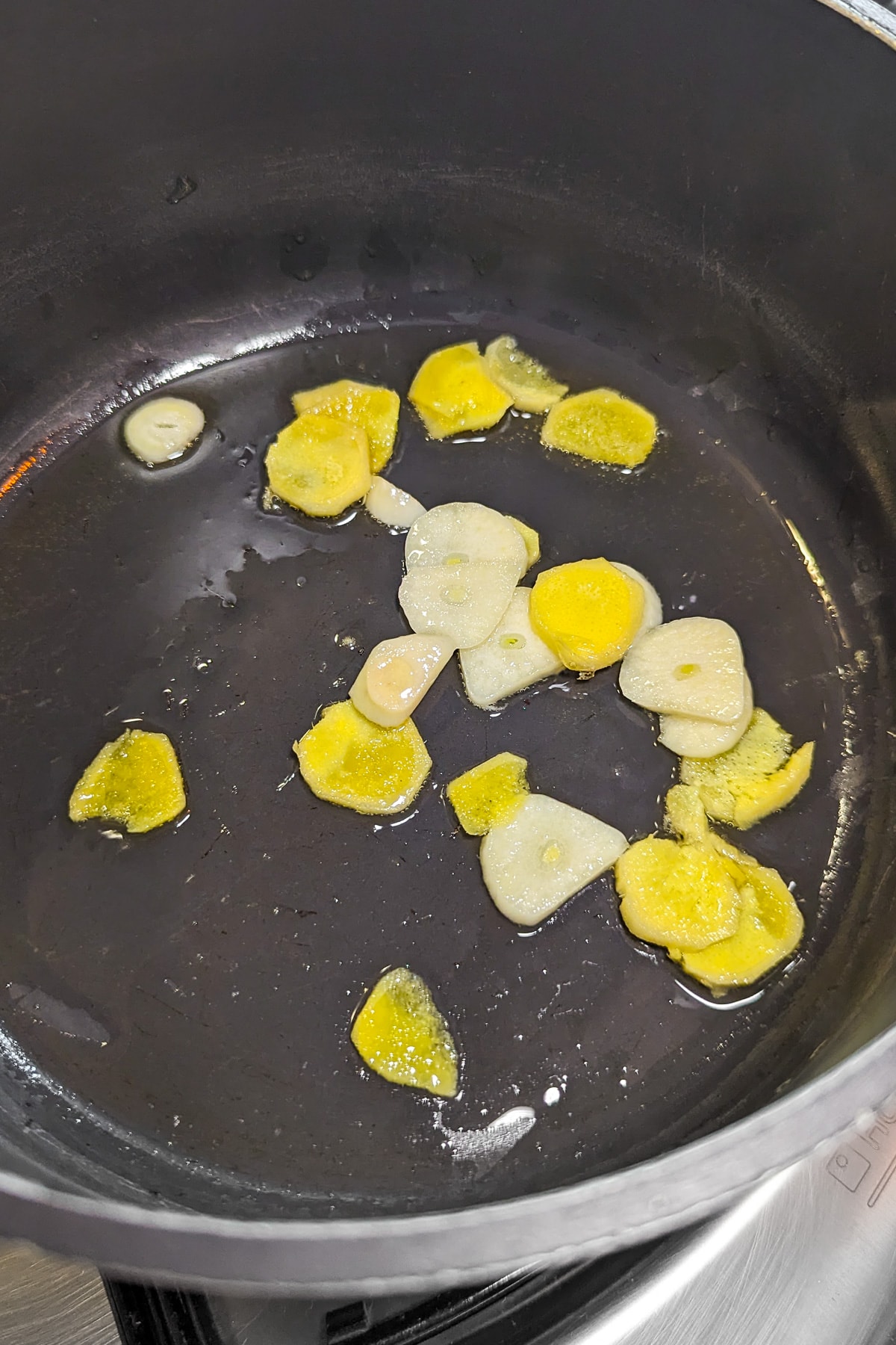 Frying ginger and garlic in a pan on the stove.