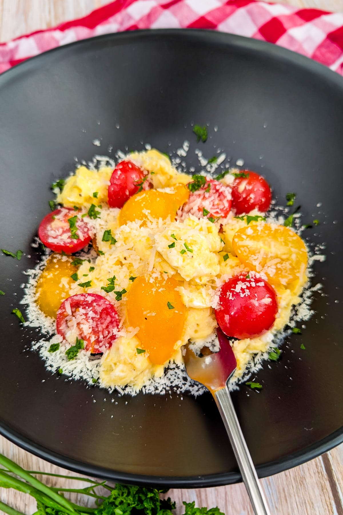 Close look of tomato and egg scramble with parmesan and parsley.