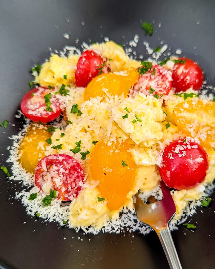 Close look of tomato and egg scramble with parmesan and parsley.