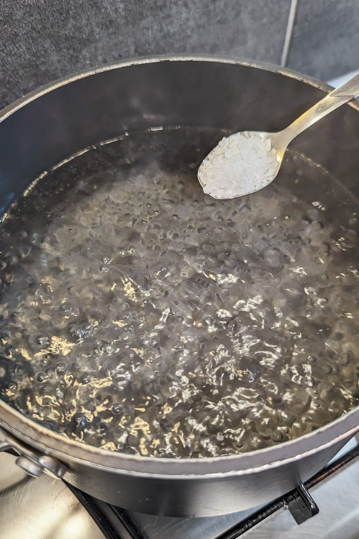 A teaspoon with salt over a pan with boiling water.