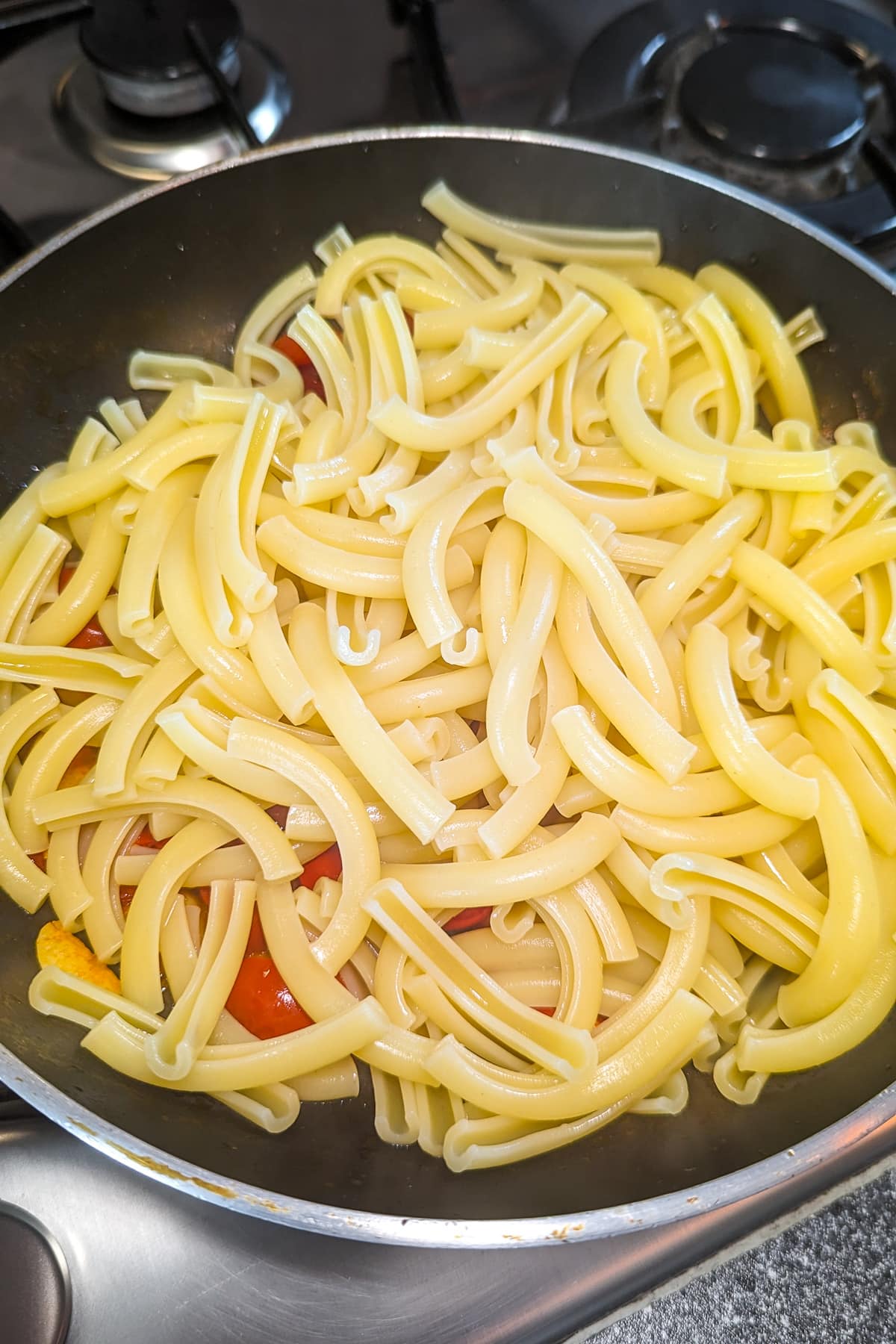 Close look of a pan of pasta with tomatoes, and garlic.