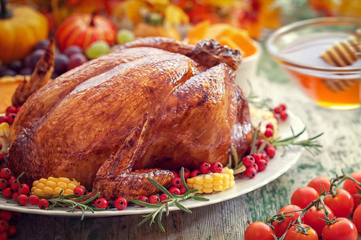 Side view of a roasted turkey near a small pot with honey.