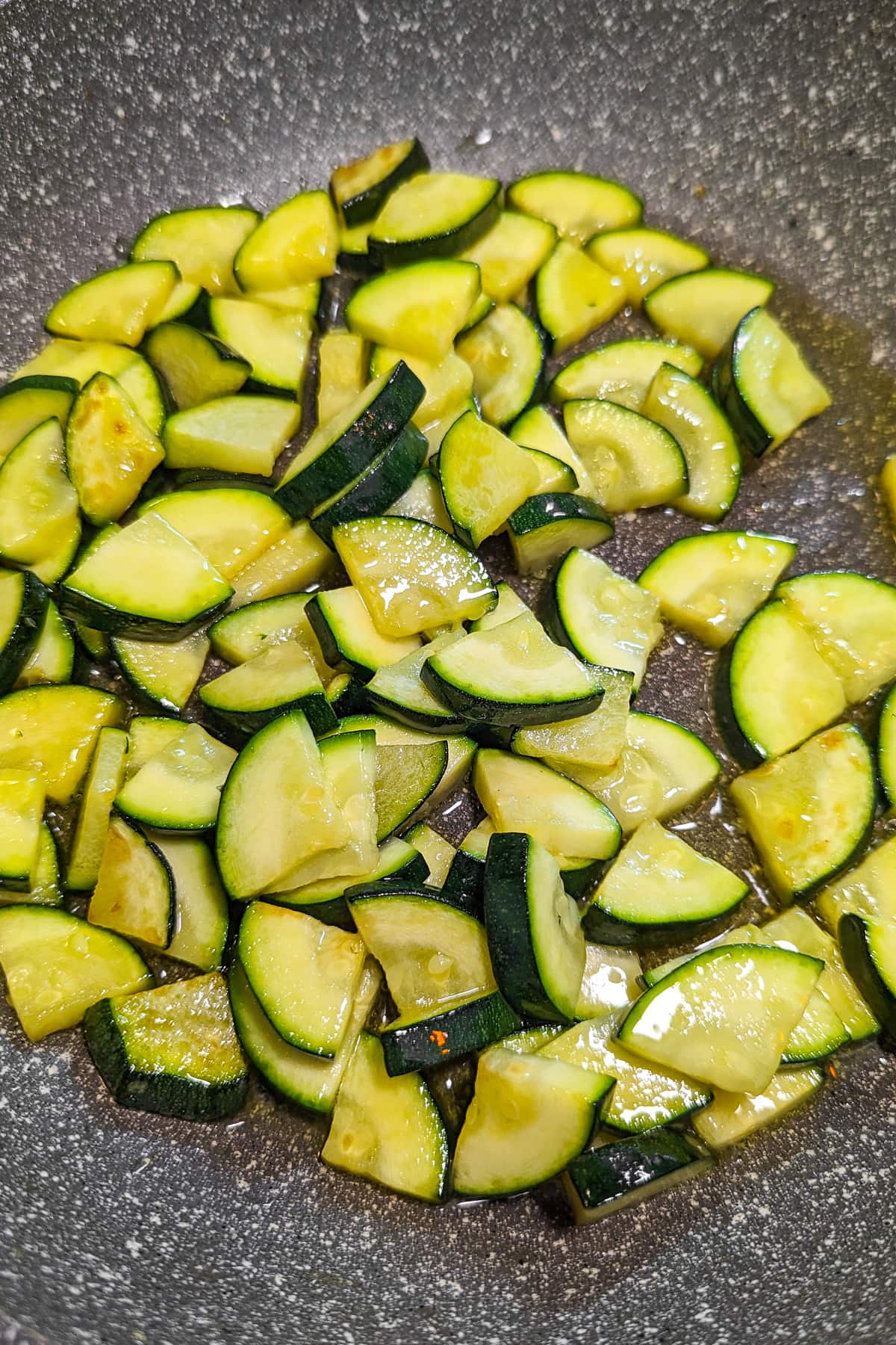 Frying zucchini slices in a frying pan.