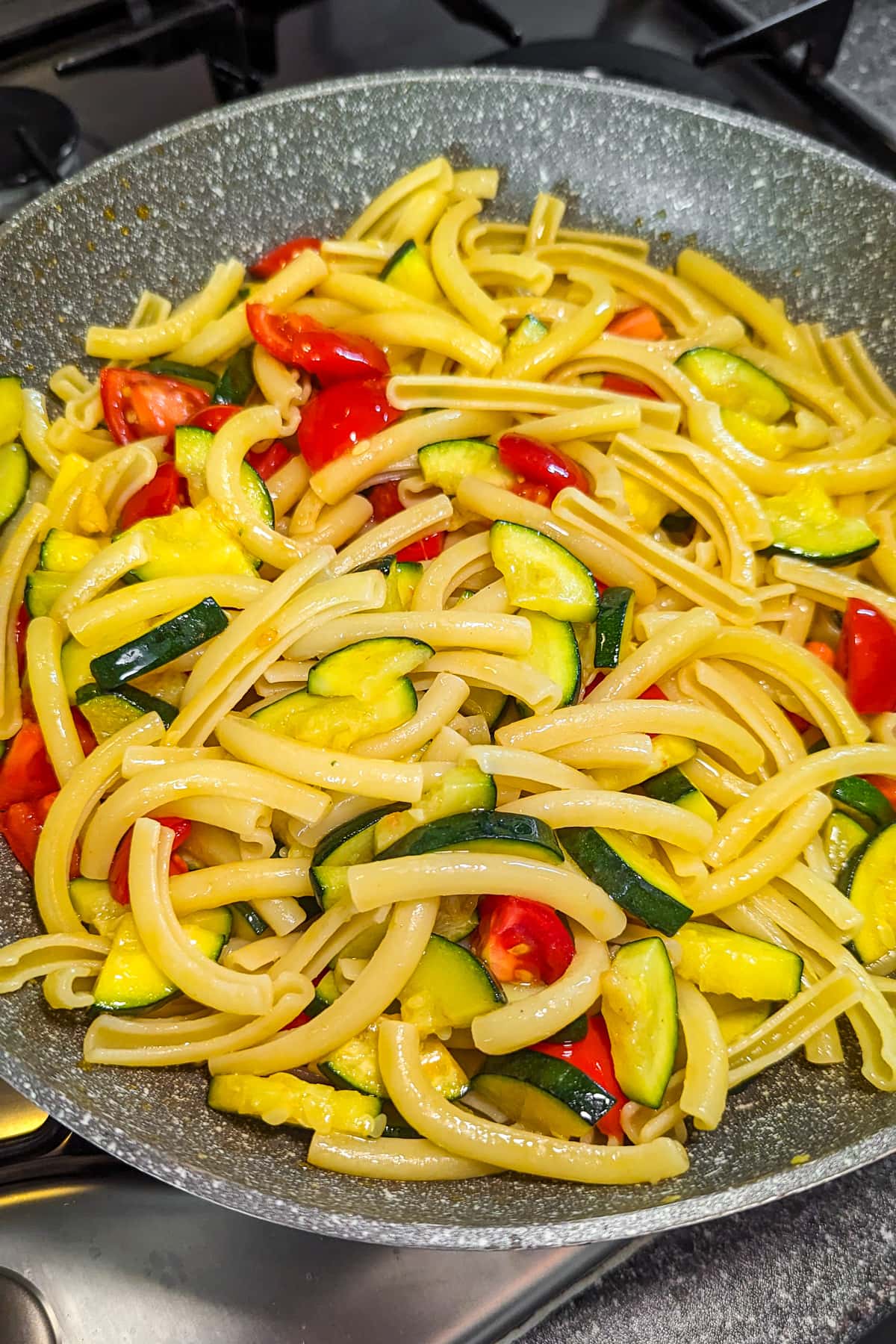 Zucchini and tomato pasta in a frying pan.