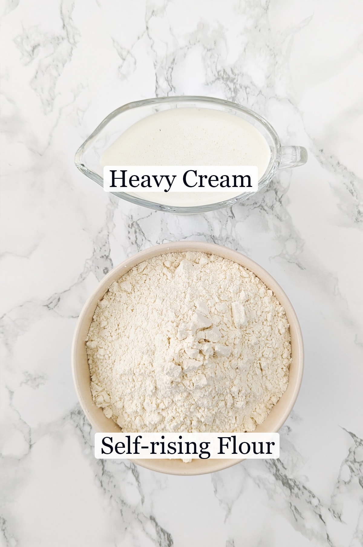 Transparent bowl with heavy cream and self-rising flour near it.
