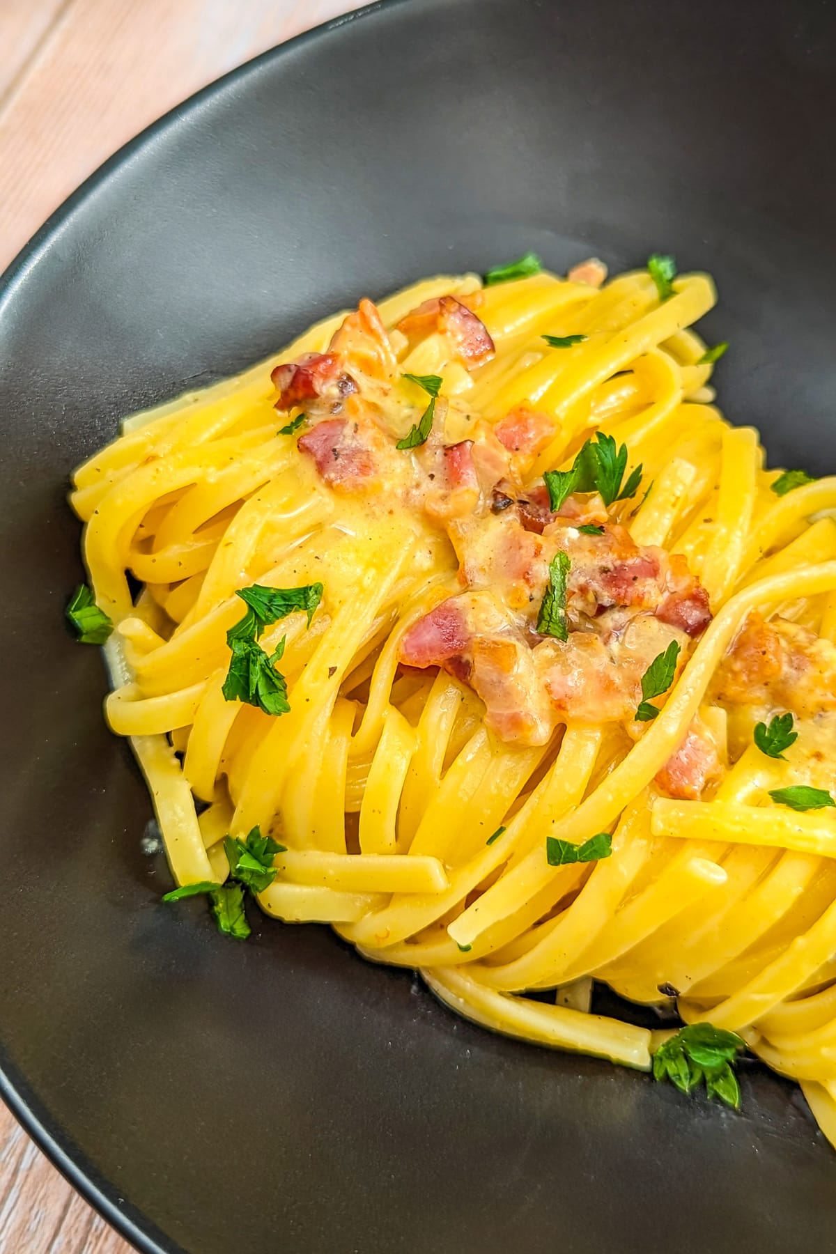 Carbonara pasta with bacon and decorated with freshly chopped parsley.