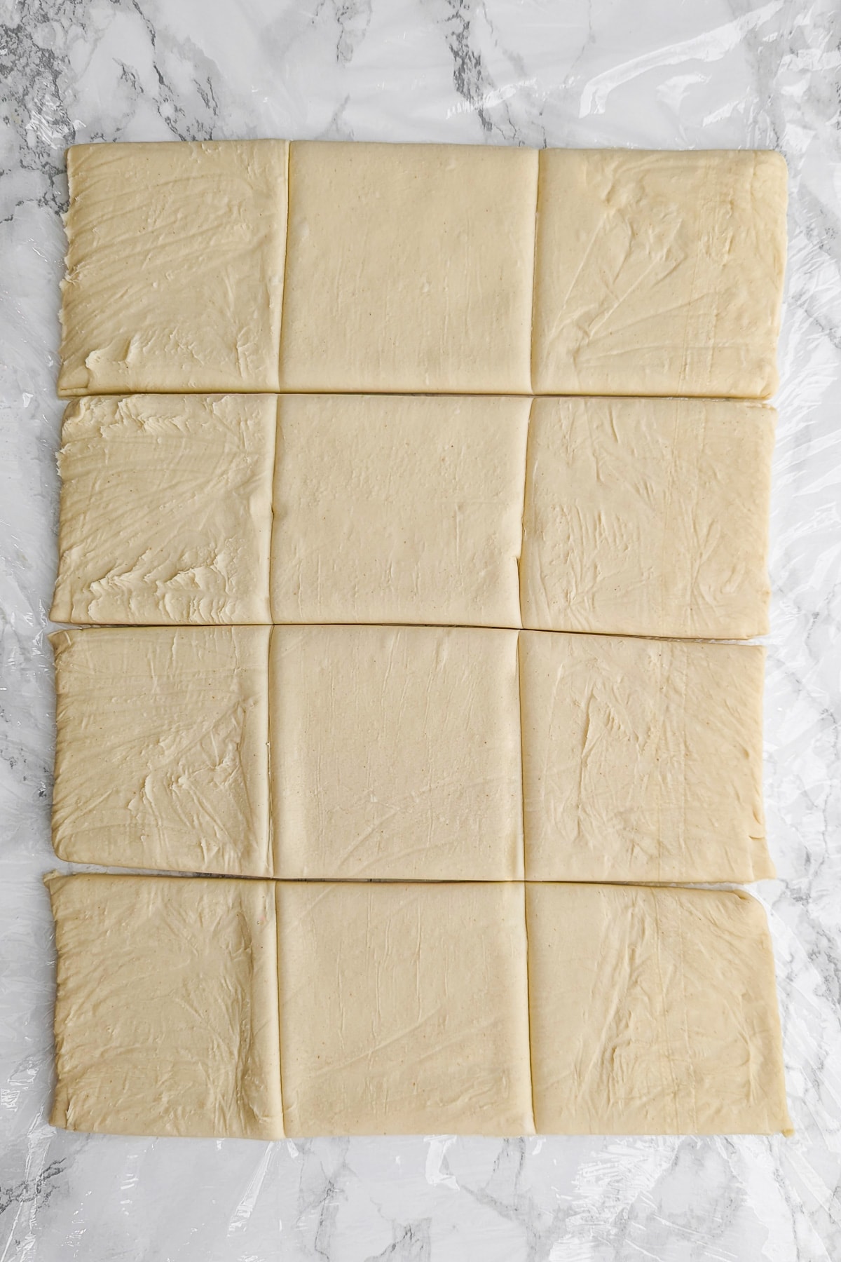 A sheet of dough divided into 12 squares of the same size.