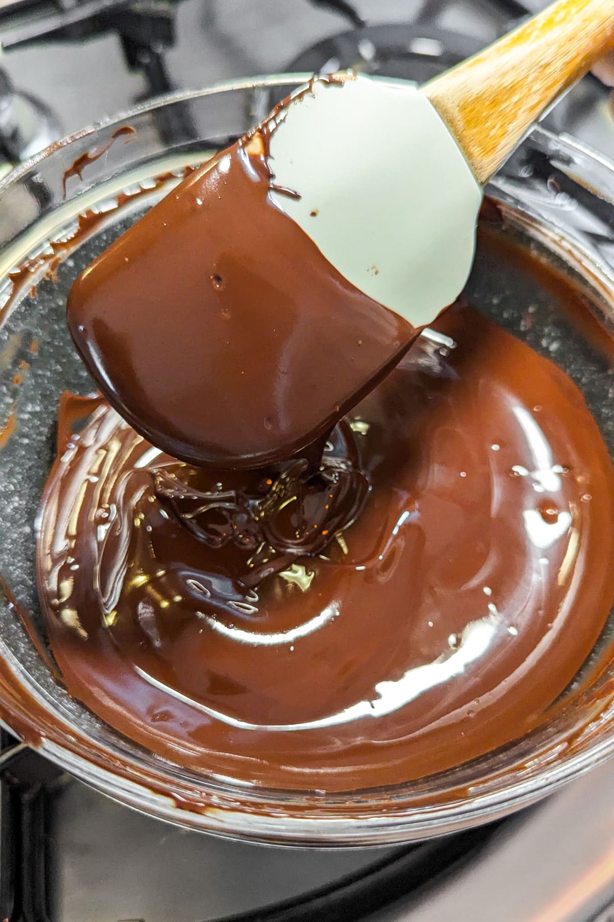 Melting chocolate in a transparent bowl on the stove.
