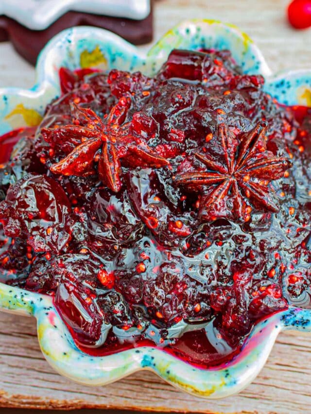 Colorful bowl with Christmas jam in it on a wooden surface.