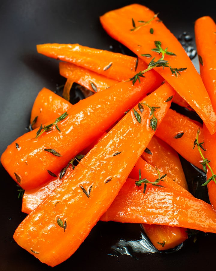 Glazed carrots with thyme in a black plate.